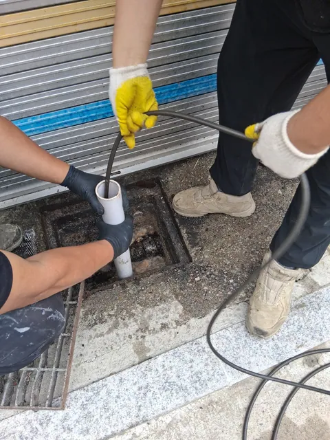 외부 점검구에서 장갑을 착용하고 배관 작업을 진행하는 모습