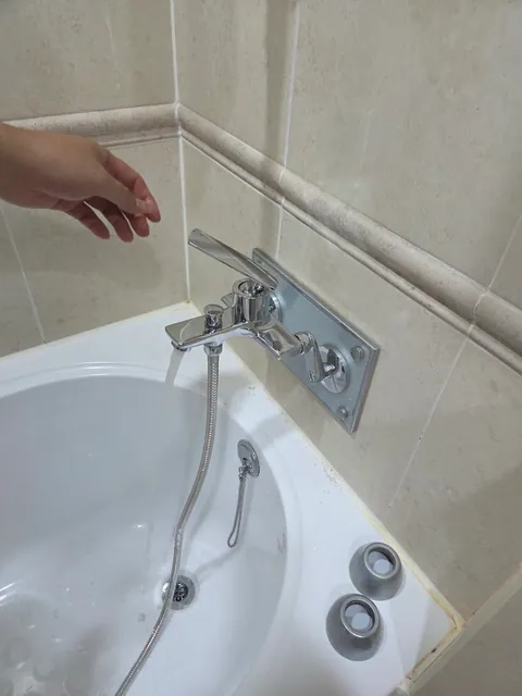 욕실 벽면에 설치된 수전과 샤워 호스