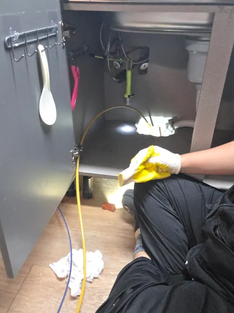 싱크대 하부장에서 배관 점검 케이블을 다루는 작업자